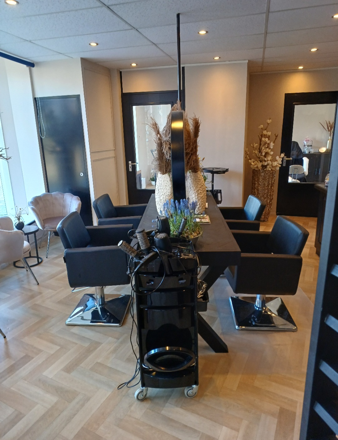 Het midden van de salon: een zwarte kaptafel met vier stoelen op een visgraatvloer